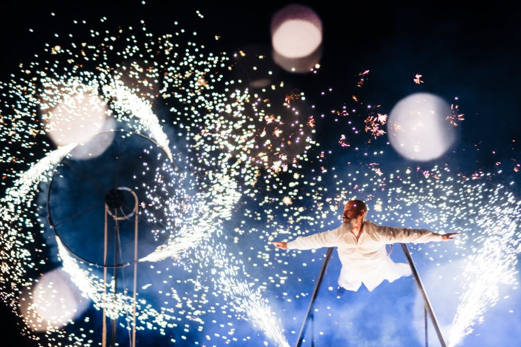 A performer flying in the air surrounded by fireworks